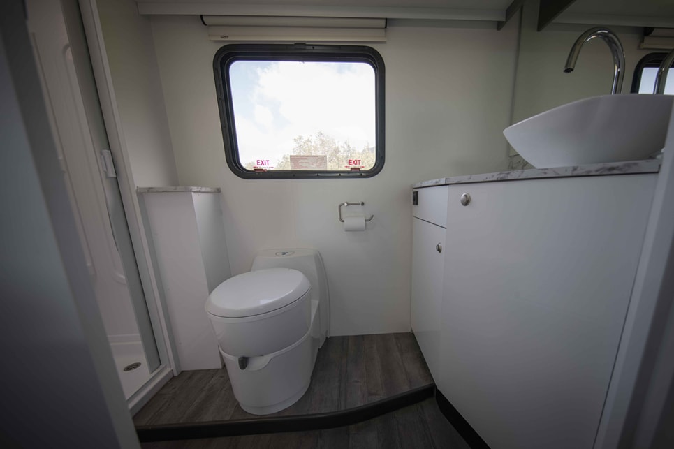The bathroom features a shower, toilet, raised porcelain basin on the vanity and towel hooks.