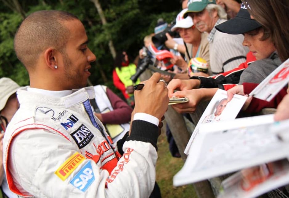 Lewis Hamilton signs autographs for fans. 