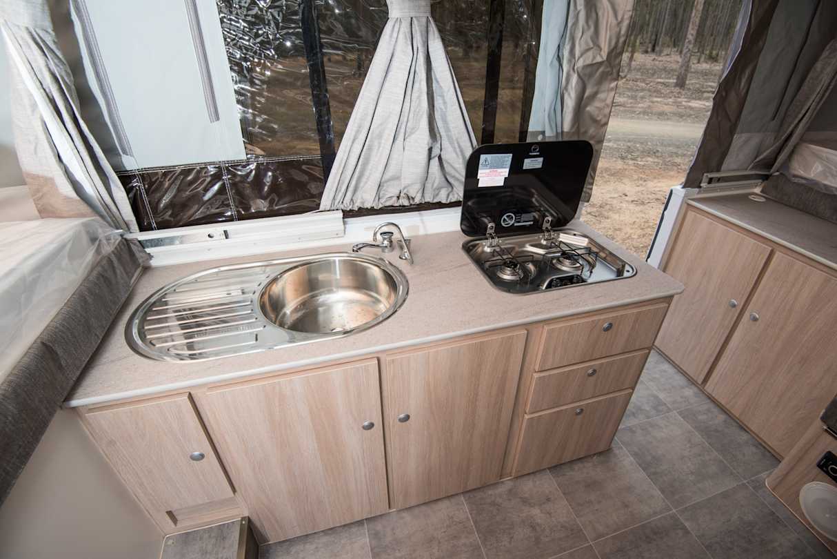 The kitchen includes a sink, two-burner hob, and 90-litre Dometic fridge. (image credit: Brendan Batty)