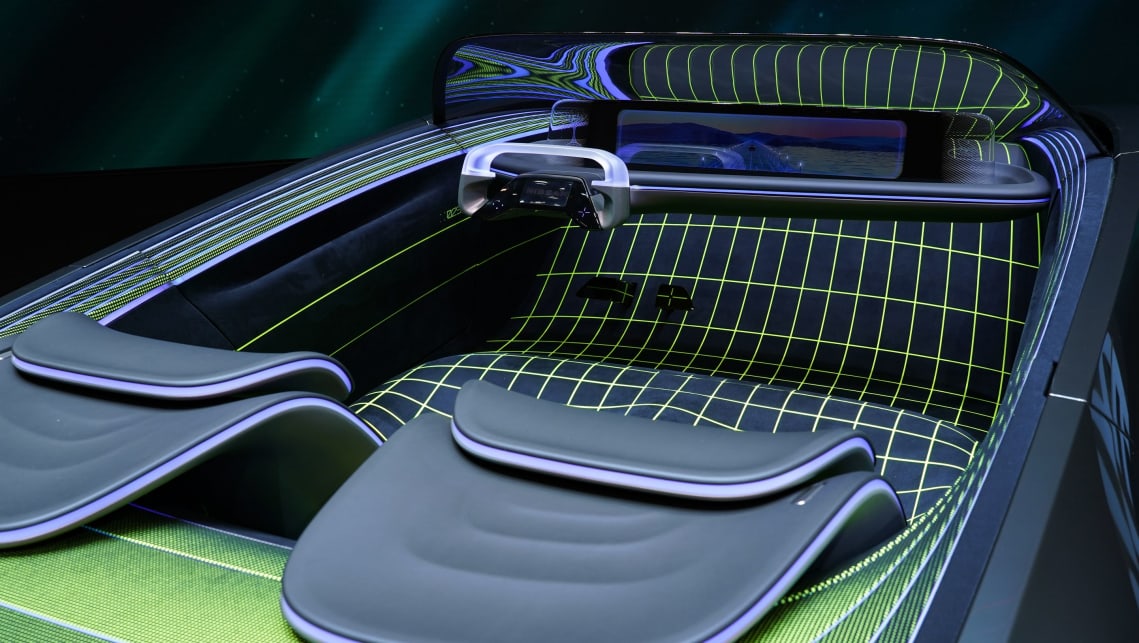 The interior has a cascading seat design, with a two-spoke oval steering wheel.